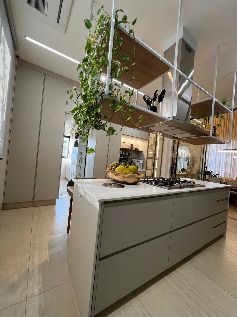 Cozinha gourmet contemporânea com ilha central, cooktop, coifa em inox e armários planejados de alta precisão
